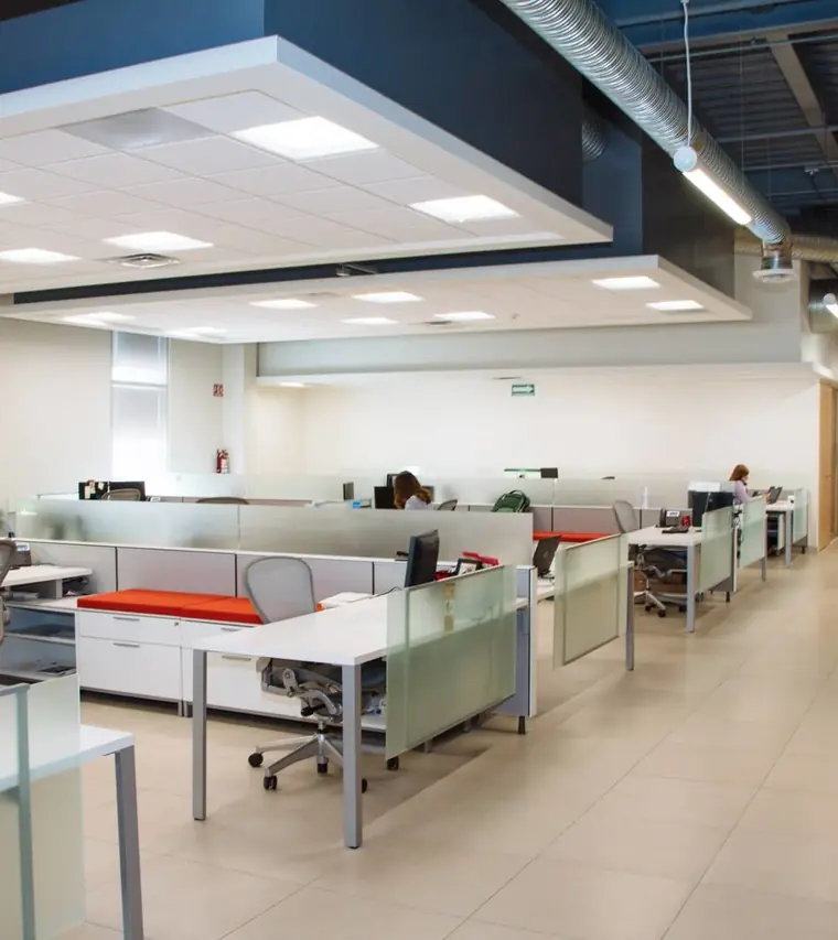 Bright open-plan office with desks, glass partitions and polished tile floors